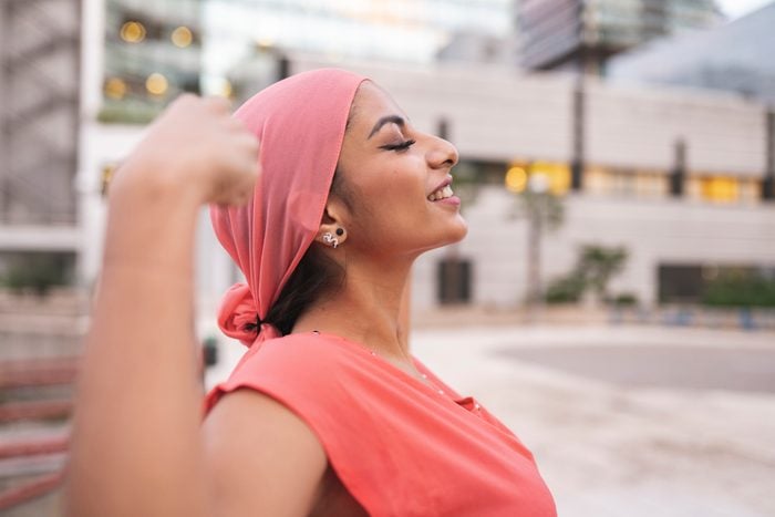 pretty with pink cancer scarf woman with raised arms showing muscle