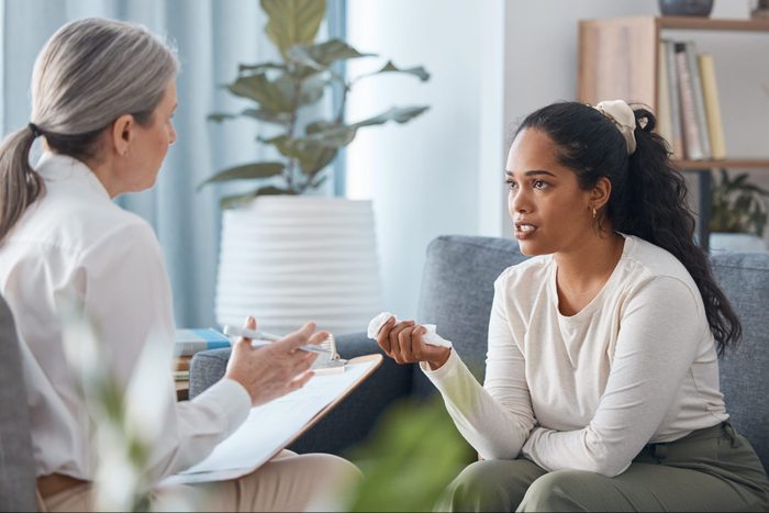 Shot of a young woman sitting and talking to her psychologist during a consultation
