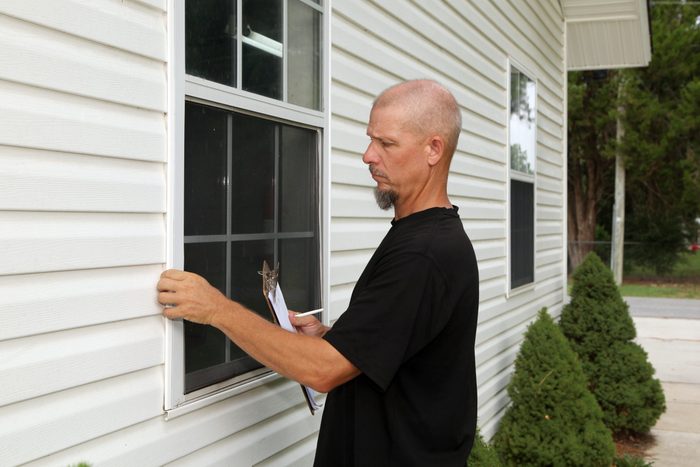 a man examining windows from the outside to make sure water isn't getting in