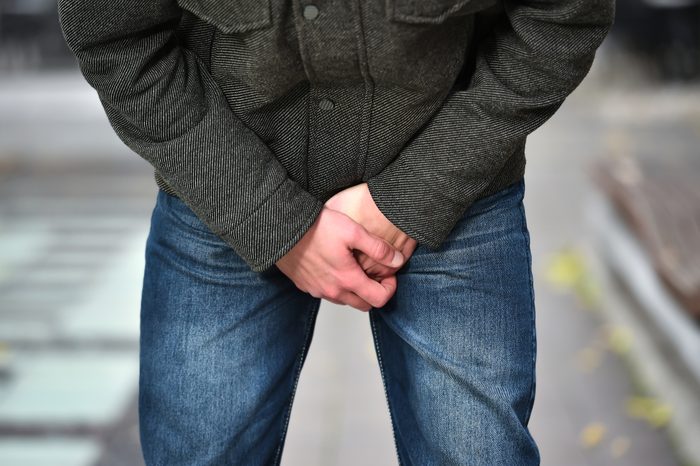anonymous man holding groin in pain outdoors