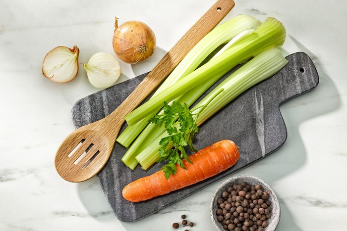 Celery Carrots And Onions on a cutting board with a wooden spoon