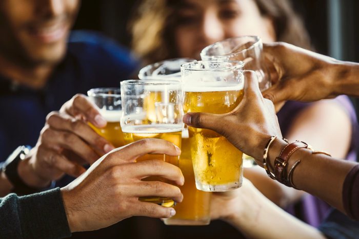 Group of friends toasting beer glasses at table in bar