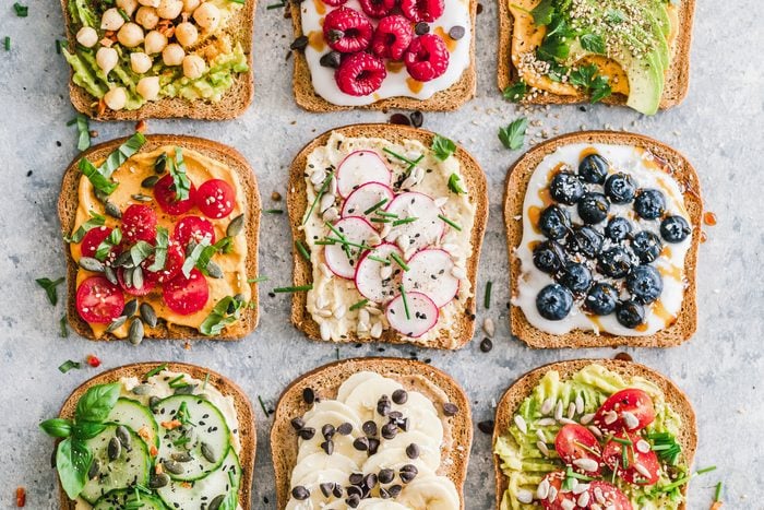 9 different slices of toast topped with different fruits, veggies, spreads and seeds