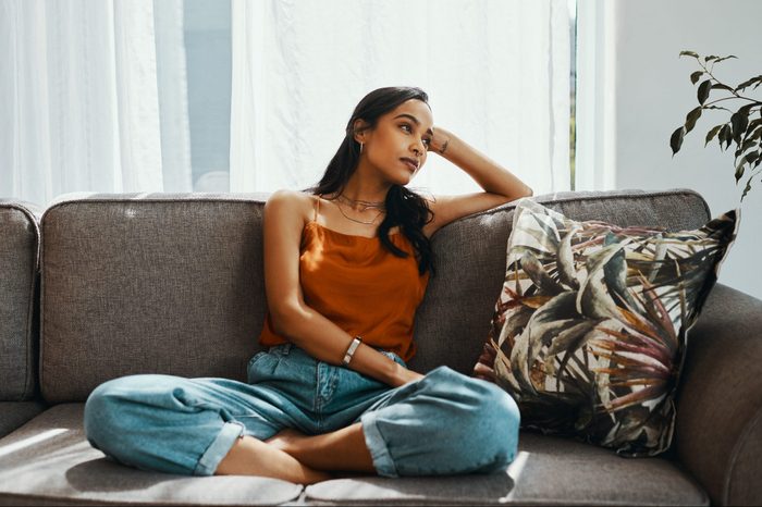 young woman looking thoughtful on the sofa at home