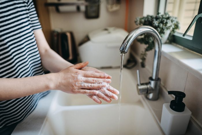 Cropped shot of a woman maintaining hands hygiene and washing hands with soap in the sink