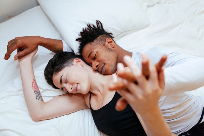 High Angle View Of Couple Lying On Bed At Home