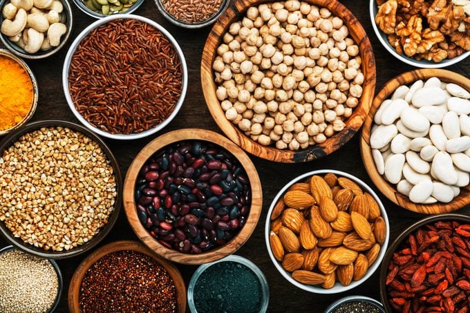 Superfoods, legumes, nuts, seeds and cereals set in bowls on wooden background