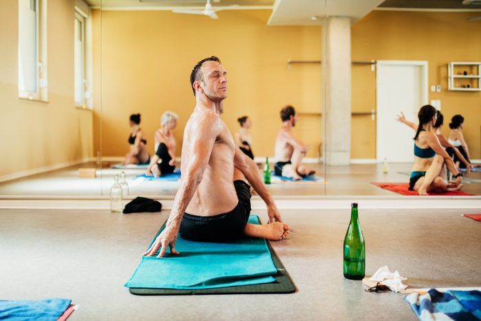 Man Sitting On Towel Twisting In Yoga Pose