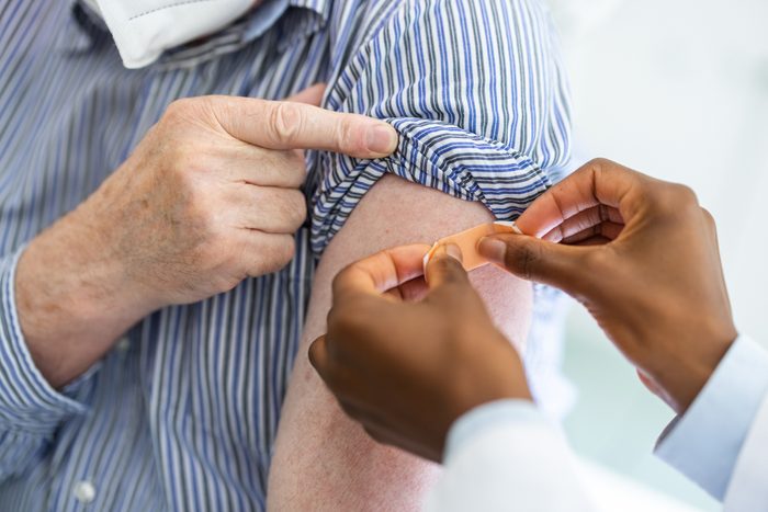 Close-up of a doctor putting a band-aid on the arm of a male after giving vaccine