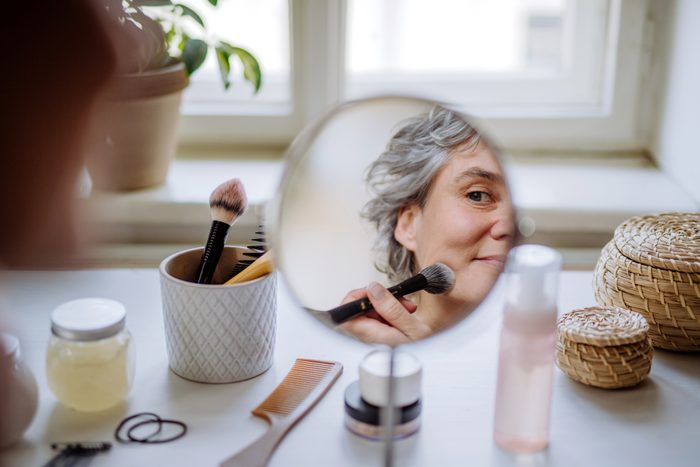 Mature woman applying a make up at home.
