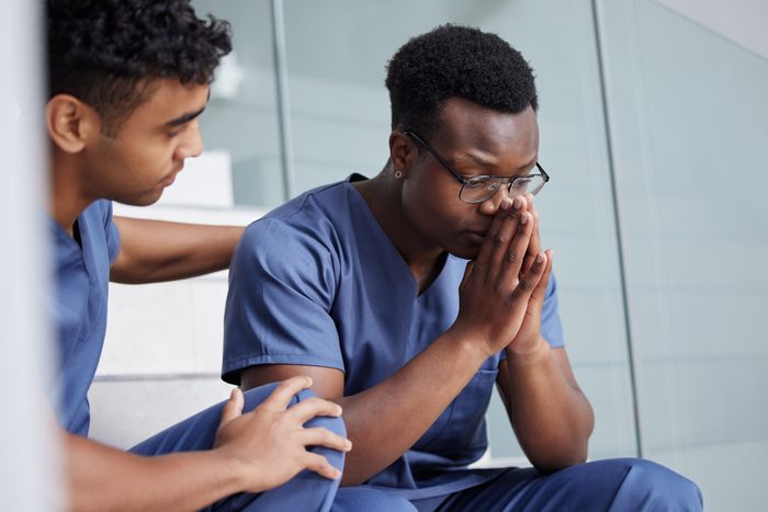 young male doctor consoling a stressed coworker at work