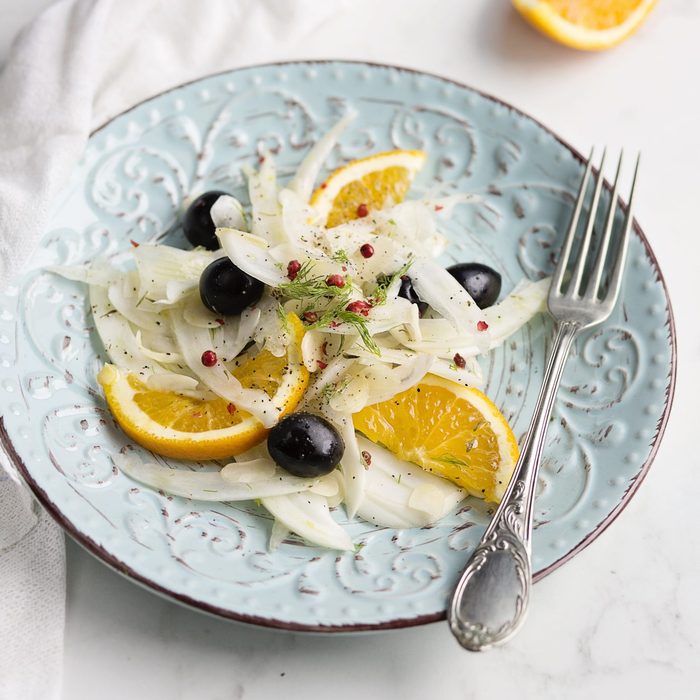 Fennel salad with black olives, orange and almond flakes on white and bright background