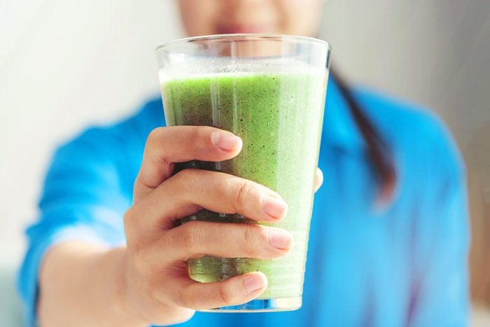 Midsection Of Woman Holding a green Smoothie