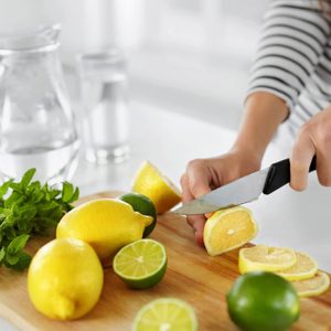 woman's hands slicing lemons and limes for flavored water