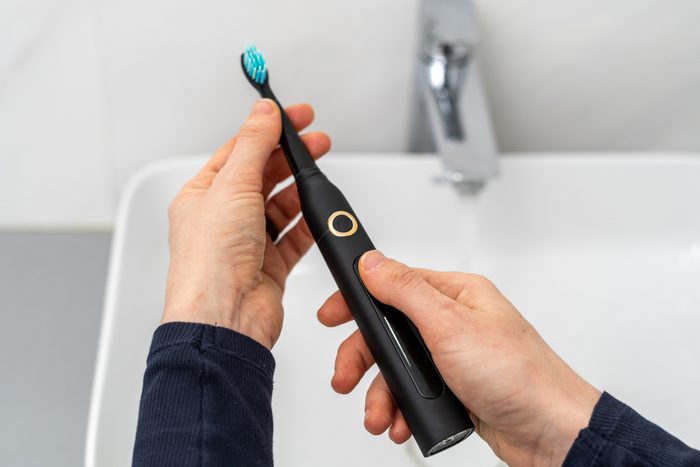 hands holding an Electric toothbrush about to replace the toothbrush head