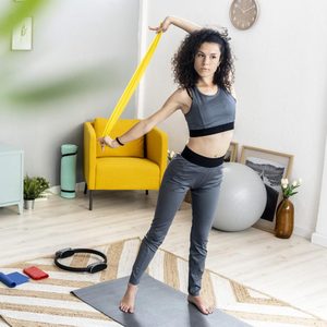 Young woman looking away while exercising with resistance band at home