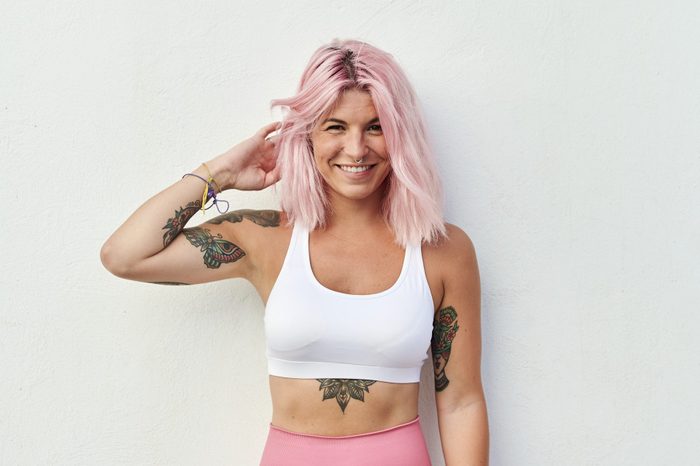 Portrait of woman with pink hair in front of white wall