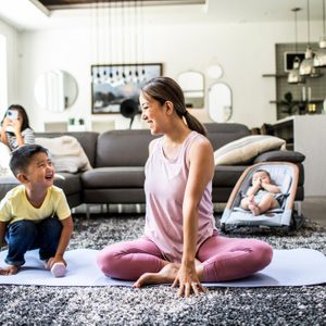 Mother doing yoga at home surrounded by children