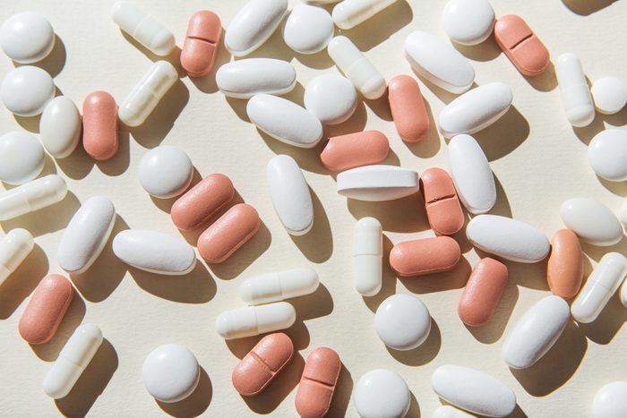 White and pink pills and capsules on white background.