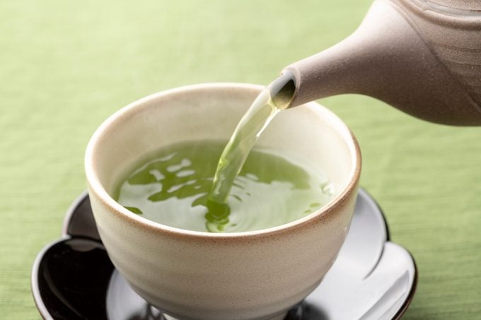Warm green tea being poured into a tea cup