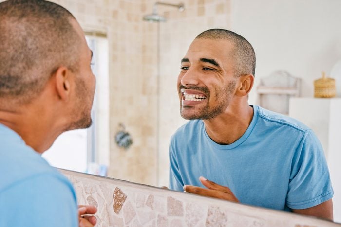 Shot of a young man admiring his freshly brushed teeth in the bathroom mirror at home