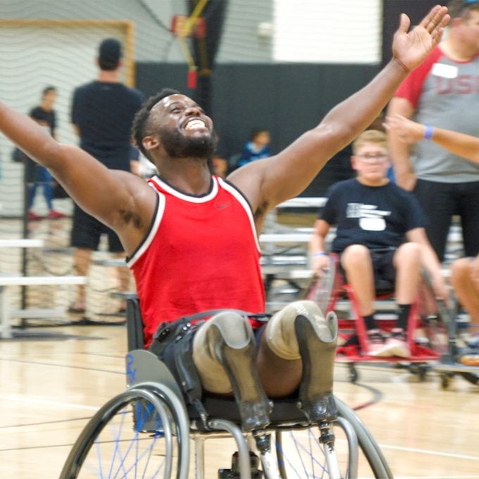 Blake Leeper on a basketball court in a wheelchair, smiling with his hands in the air