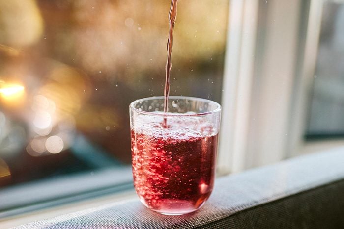 Berry Juice being poured into a clear glass near a window