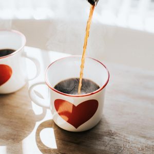 pouring coffee into a mug with a heart on it