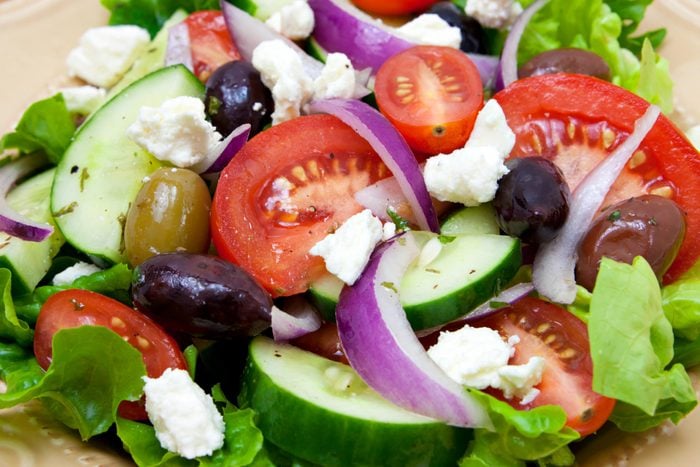 close up of green salad with olives, tomatoes, onions and feta