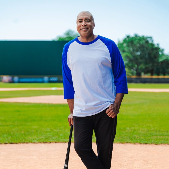 Bernie Williams on a baseball field leaning on a baseball bat