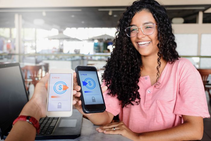 Young women sending money through digital wallet, using wireless technology