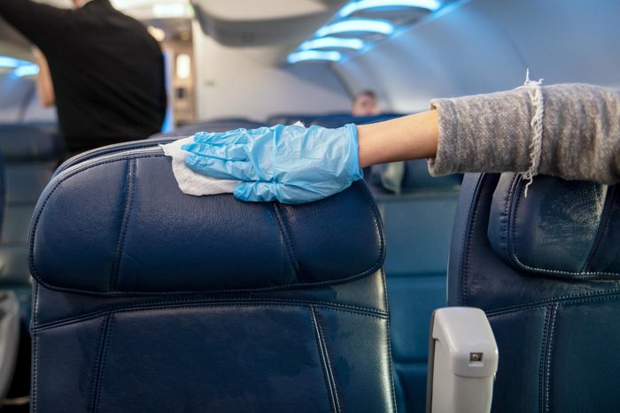 gloved hand sanitizing a plane seat