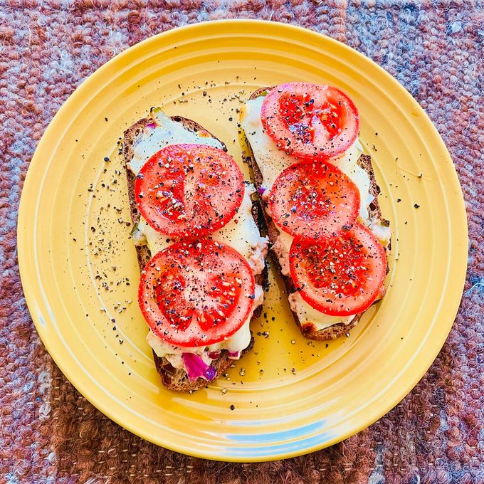 tuna salad on sourdough toast with tomatoes on yellow plate