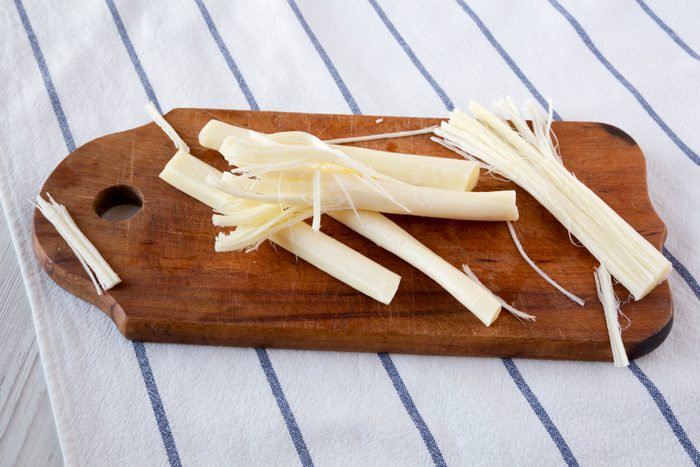 String cheese on rustic wooden board, low angle view. Healthy snack. Closeup.
