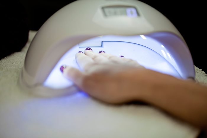 Woman Fliling Nails With UV Lamp in Background