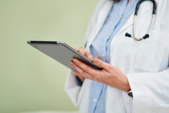 Shot of an unrecognisable doctor using a digital tablet against a green background