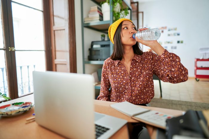 Businesswoman drinking water from bottle at workplace