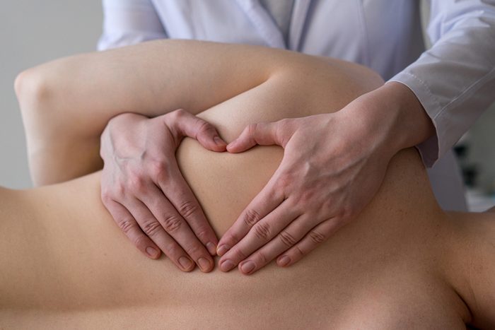 Closeup of osteopathic masseur massages patient back, relieving tension from muscles and toning up