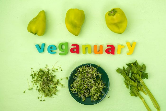Veganuary Written in magnetic letters surrounded by fresh vegetables on a green background
