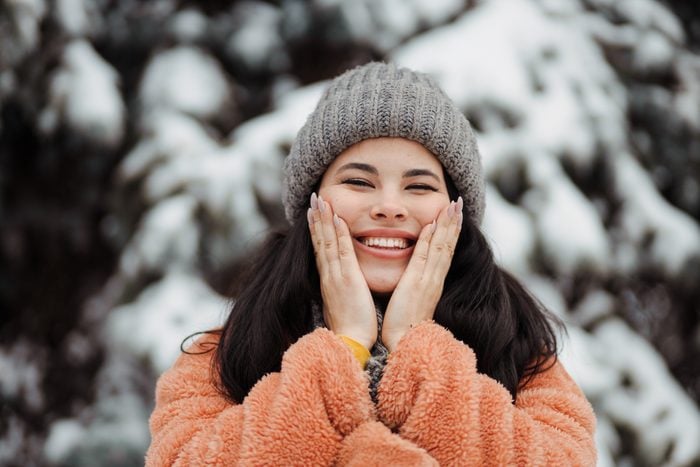 Happy pretty young woman using a sking protection cream in winter