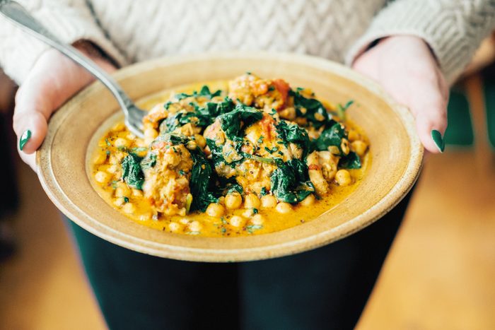 hands holding a plate with Chickpea And Spinach Curry