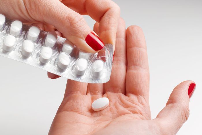 white pill being removed from the pack into a woman's hand