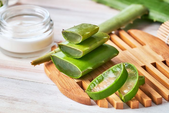 Aloe vera slices and moisturizer on a wooden table. Beauty treatment concepts