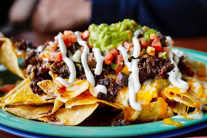 a plate piled with beef and cheese nachos