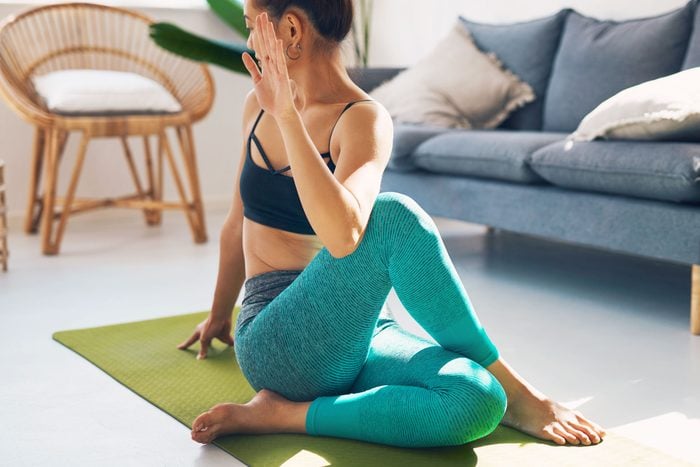woman stretching on a yoga mat in her living room