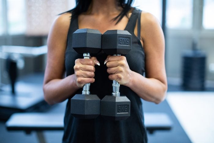 Unrecognizable woman exercising with dumbbells in the gym