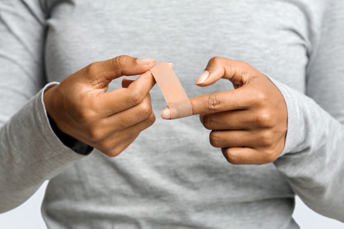 Afro woman using adhesive tape on injured finger