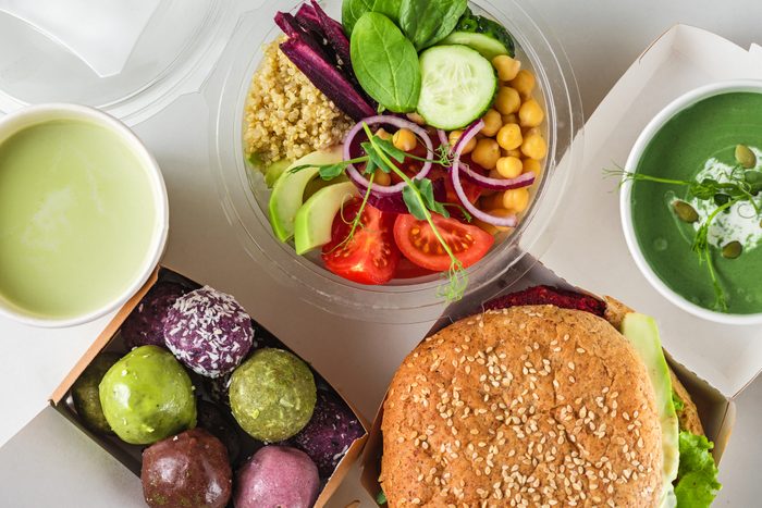 Healthy vegan food delivery. Packed burger, buddha bowl salad, green soup, energy balls and matcha latte. top view