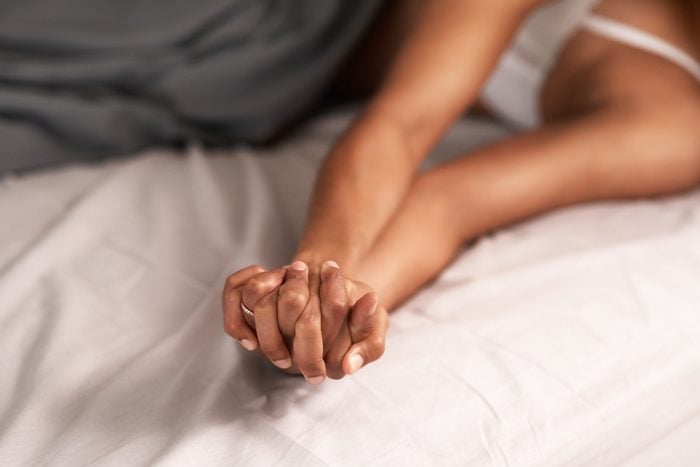 anonymous couple being intimate and holding hands with outstretched arms in their bedroom