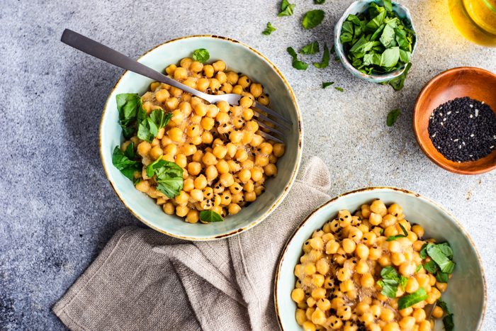 Two bowls of chickpeas with black sesame seeds and coriander